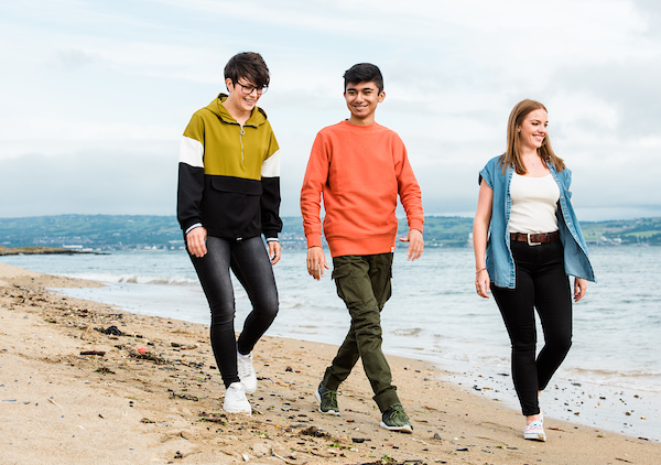 two adult females with teenage boy walking on beach