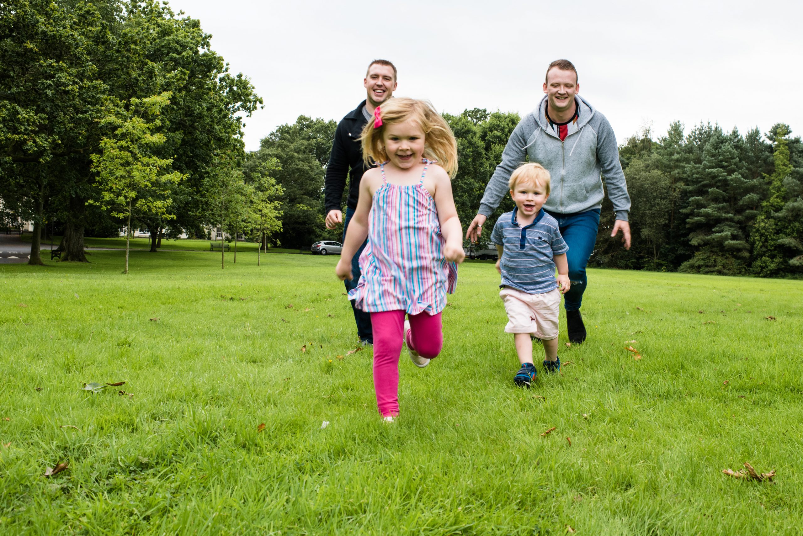 two adult male playing with two children in a park